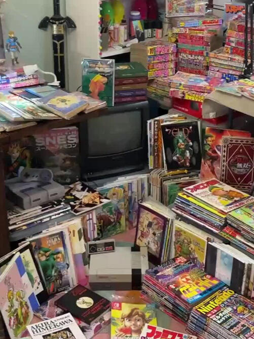 A collection of Zelda publications. Books, manga, doujinshi, etc, is scattered across tables and the floor.